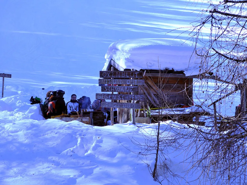 Verschneite Hütte im Abendlicht auf der Piste.
